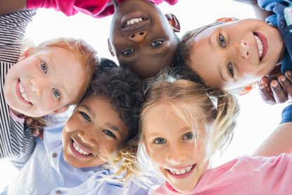 Kinder verschiedener Ethnien umarmen sich und lachen