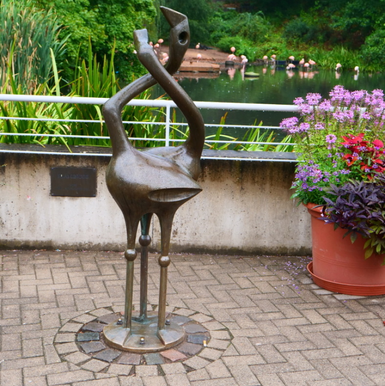 Eine Flamingoskulptur aus Bronze steht vor dem Flamingoteich im Zoo Saarbrücken