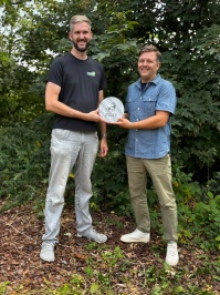Zoodirektor Jakob Kolleck und Geschäftsführer der ZGAP D. Arne Schulze stehen nebeneinander und halten zusammen die Plakette "Premiumpartner Silber".